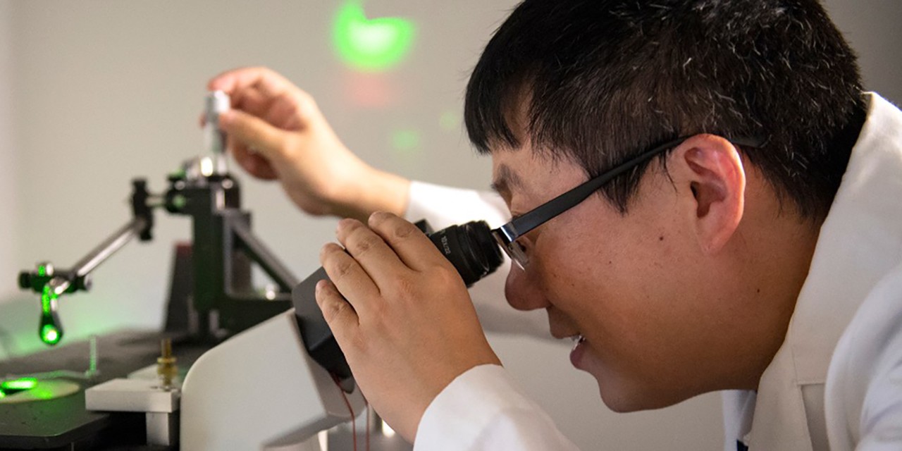 Jiajie Diao looks into a microscope