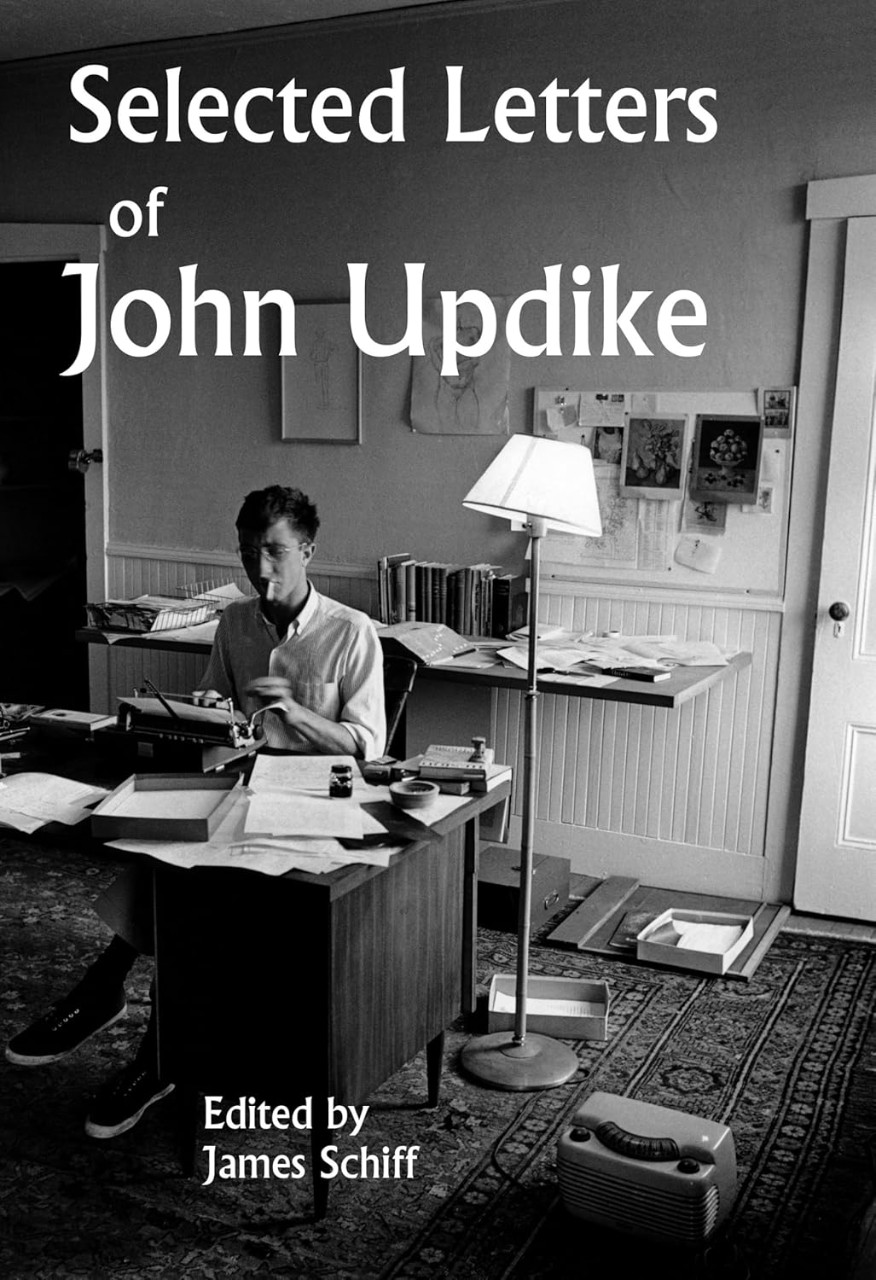book jacket for "Selected Letters of John Updike" by James Schiff. Black and white photo of Updike at his desk.