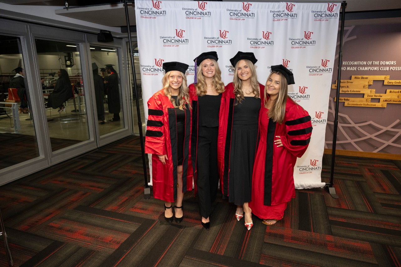 UC Law Class of 2025 pose for photos in front of stand. 