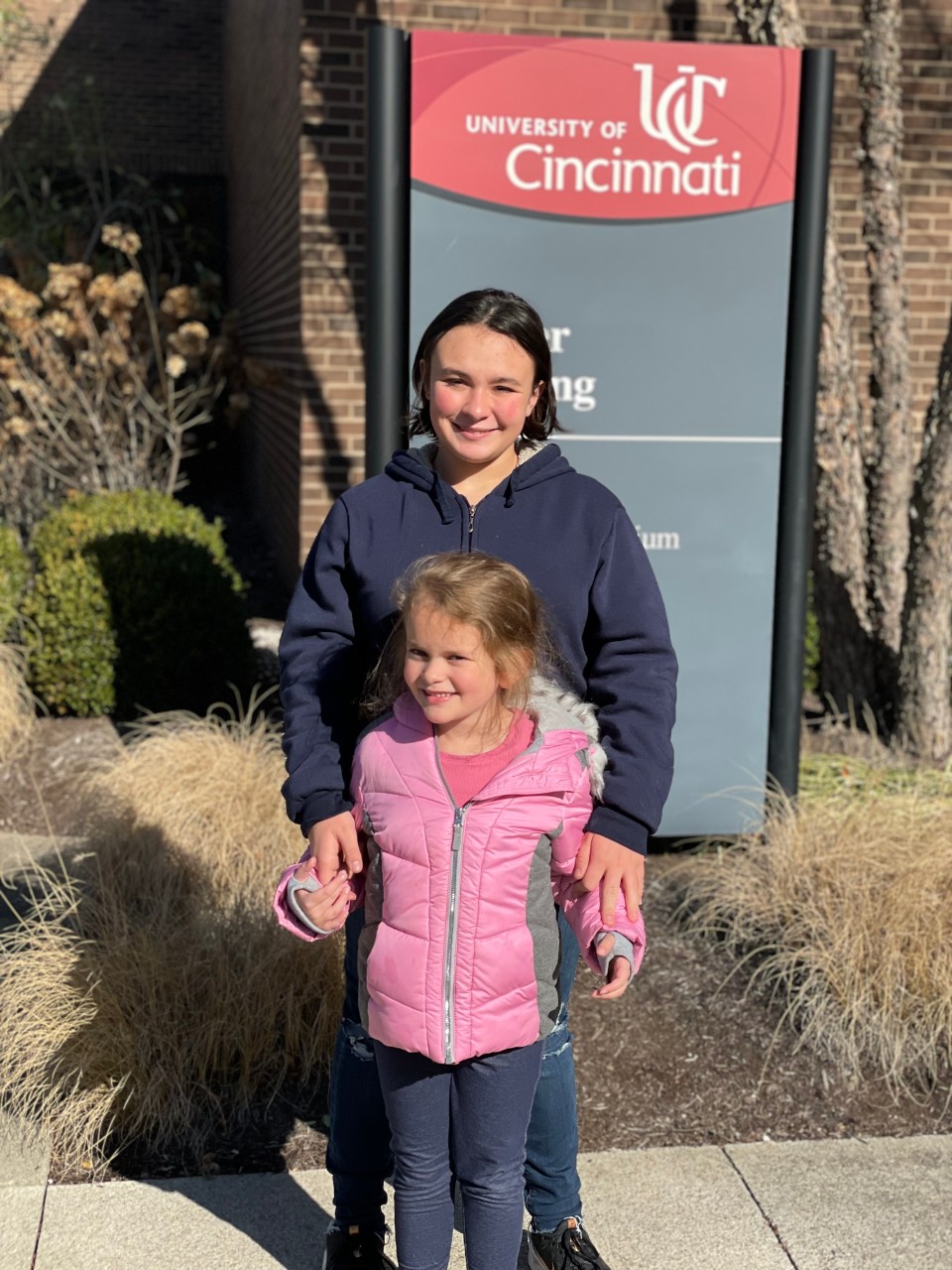 Two females outside UC sign.