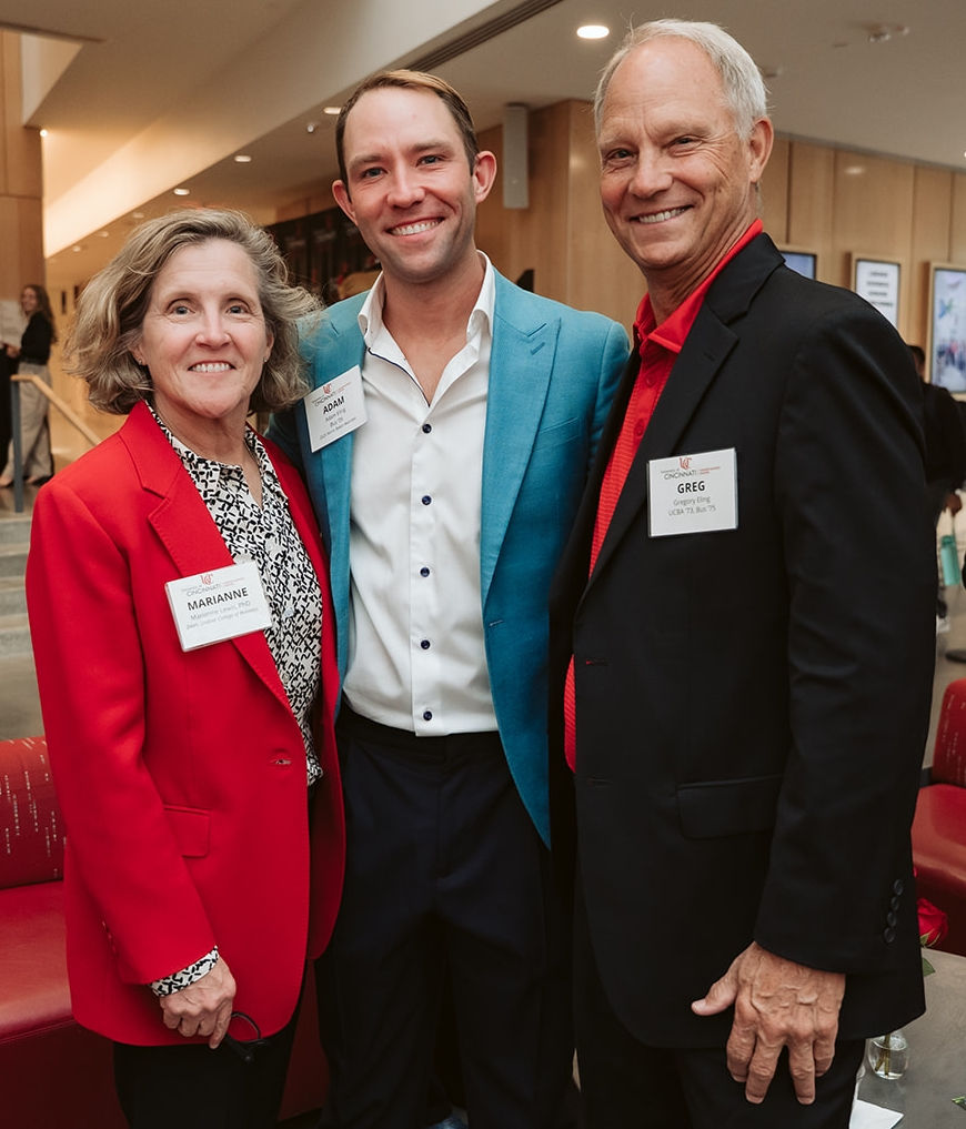 Two men, one in a black jacket and one in a teal one, pose with Dean Lewis in a red jacket.