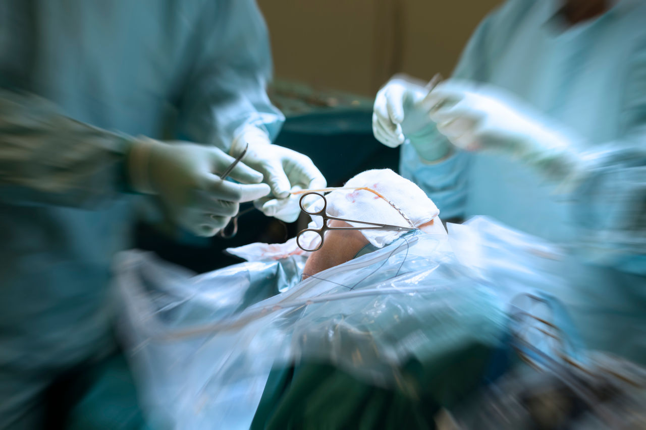A surgical team operates on a person's knee 