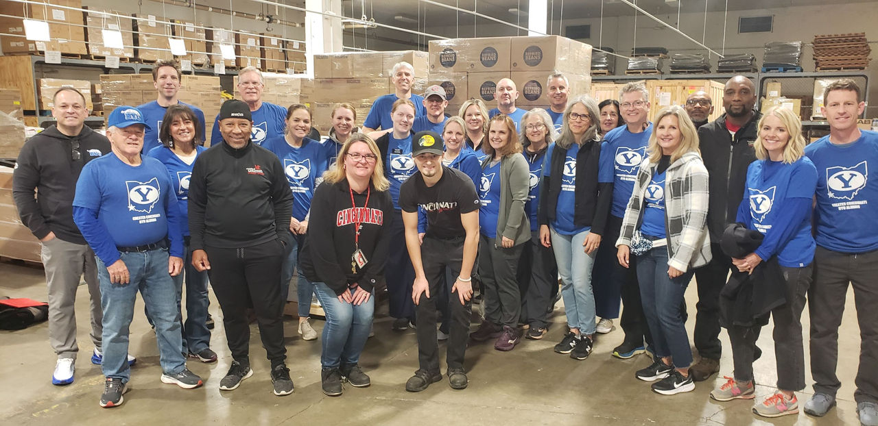 Two dozen Brigham Young University supporters join UC staff for a photo at Fishwick Building