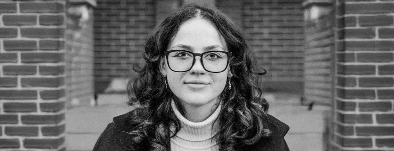 Reese Tuttle stands outside with a brick wall behind her