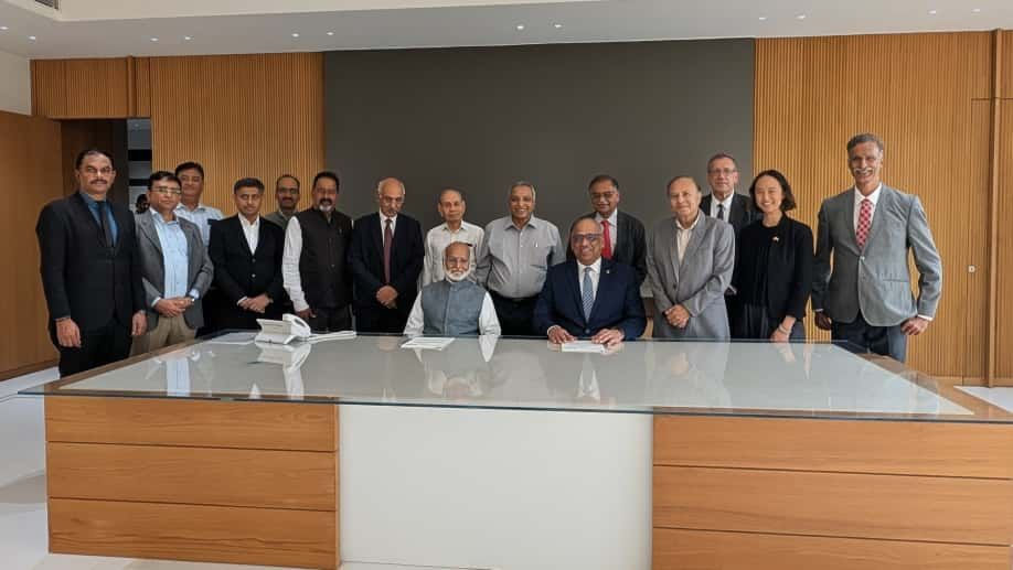 UC President Neville Pinto and Nirma President Dr. Karsanbhai K. Patel are joined by representatives from both universities during the MOU signing.