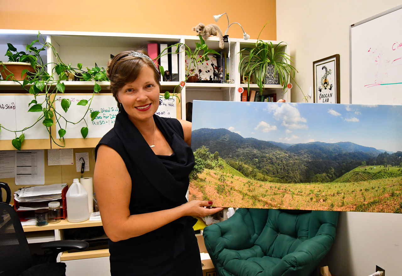 Kathleen Grogan holds up a photo depicting the mountain forests of Uganda.