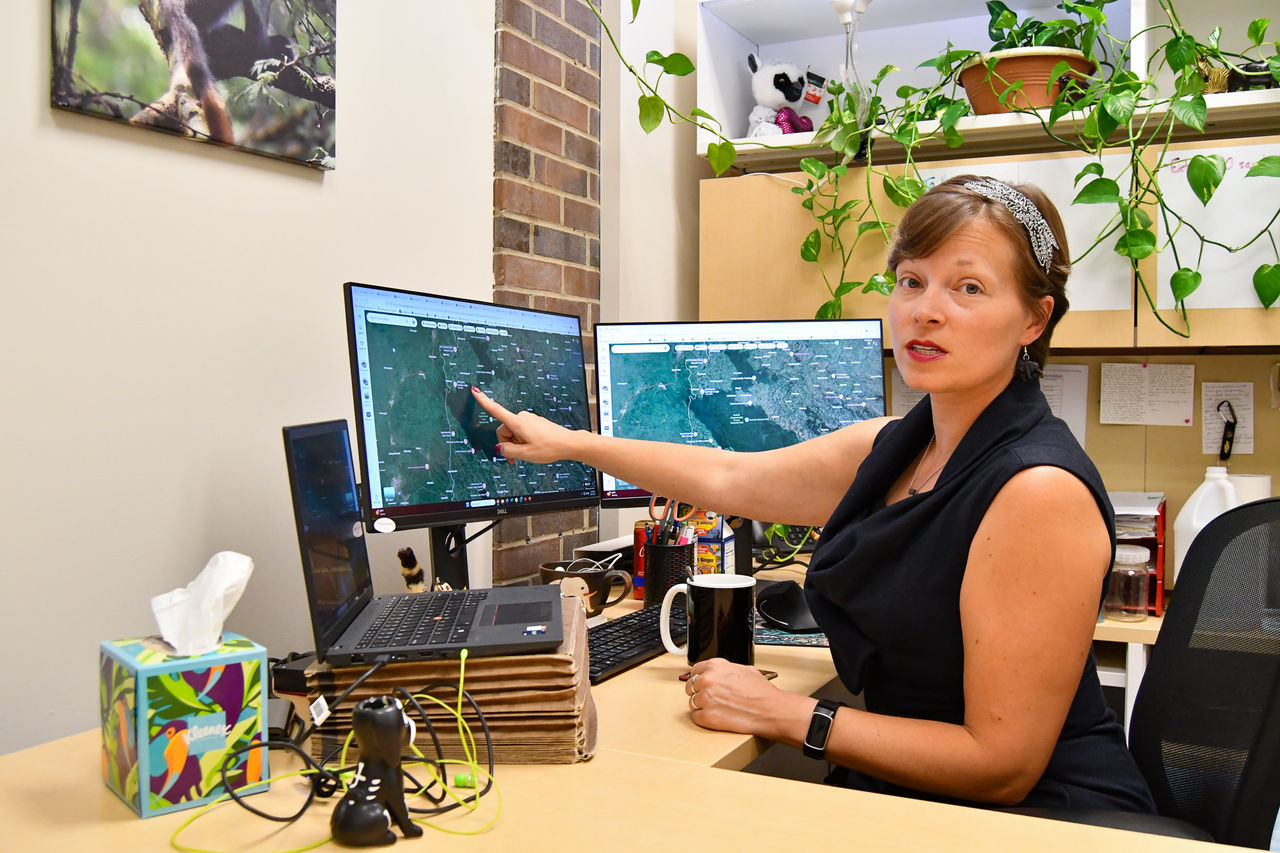 Kathleen Grogan sits at a computer displaying a map of western Uganda.