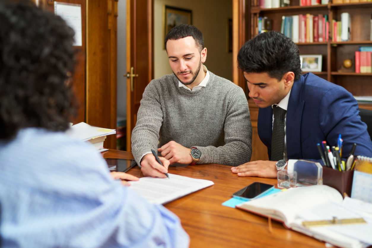 Three people sitting at a table, reviewing paperwork