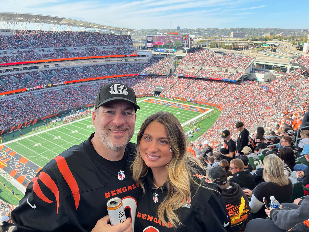 Matthew Bauer and Emma Bauer pose for a photo in Bengals spirit wear at a Cincinnati Bengals game at Paycor Stadium.