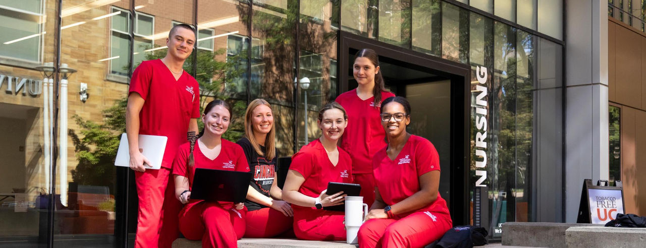Six nursing students outside. They are wearing red scrubs.