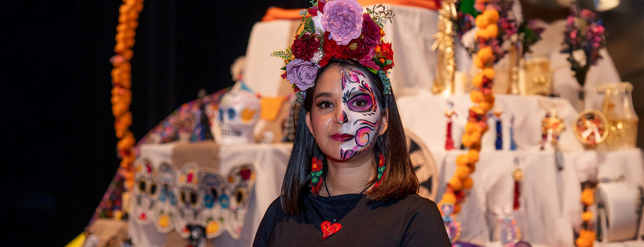 UC Clermont Assistant Professor Stephanie Alcantar stands in front of the Día de los Muertos altar constructed by students, faculty and staff for the college’s annual Spanishpalooza celebration. 