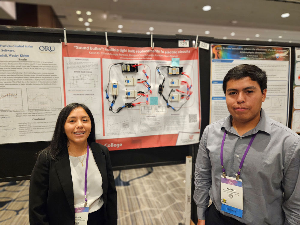 two students posing with presentation materials at conference