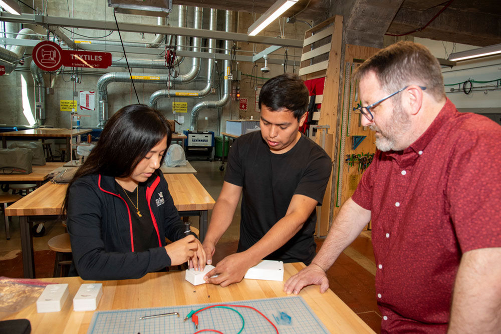 two students and a professor working in a lab