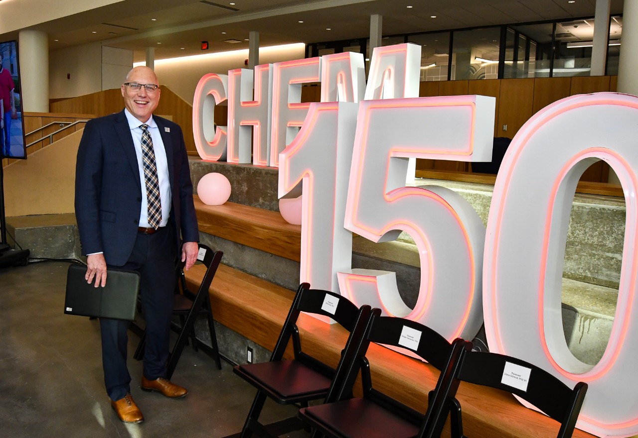 John Weidner poses in front of giant letters that say Chem 150.