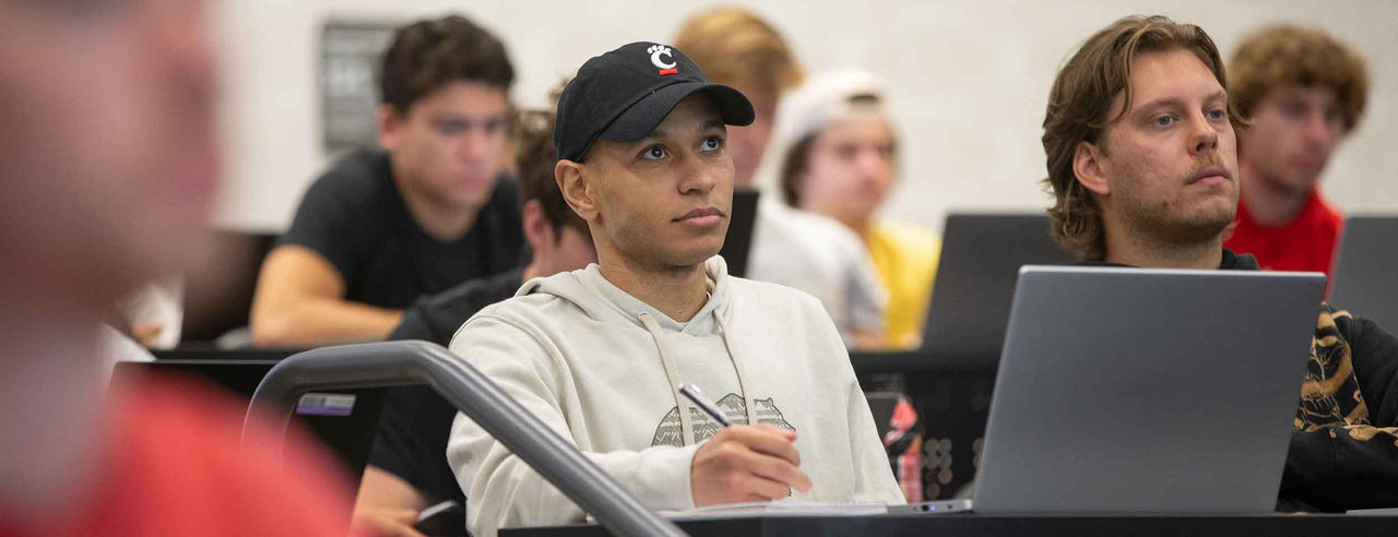 students in a classroom listen and take notes