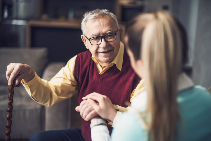 A young woman holds the hand of an elderly man 