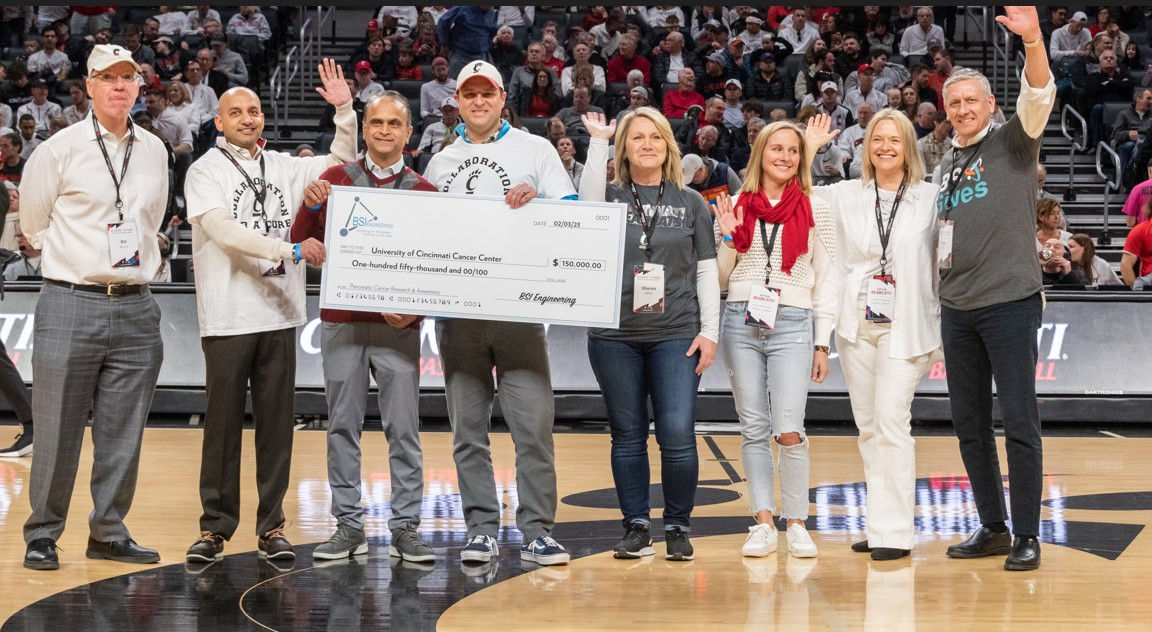Group of people on basketball court holding a big check.