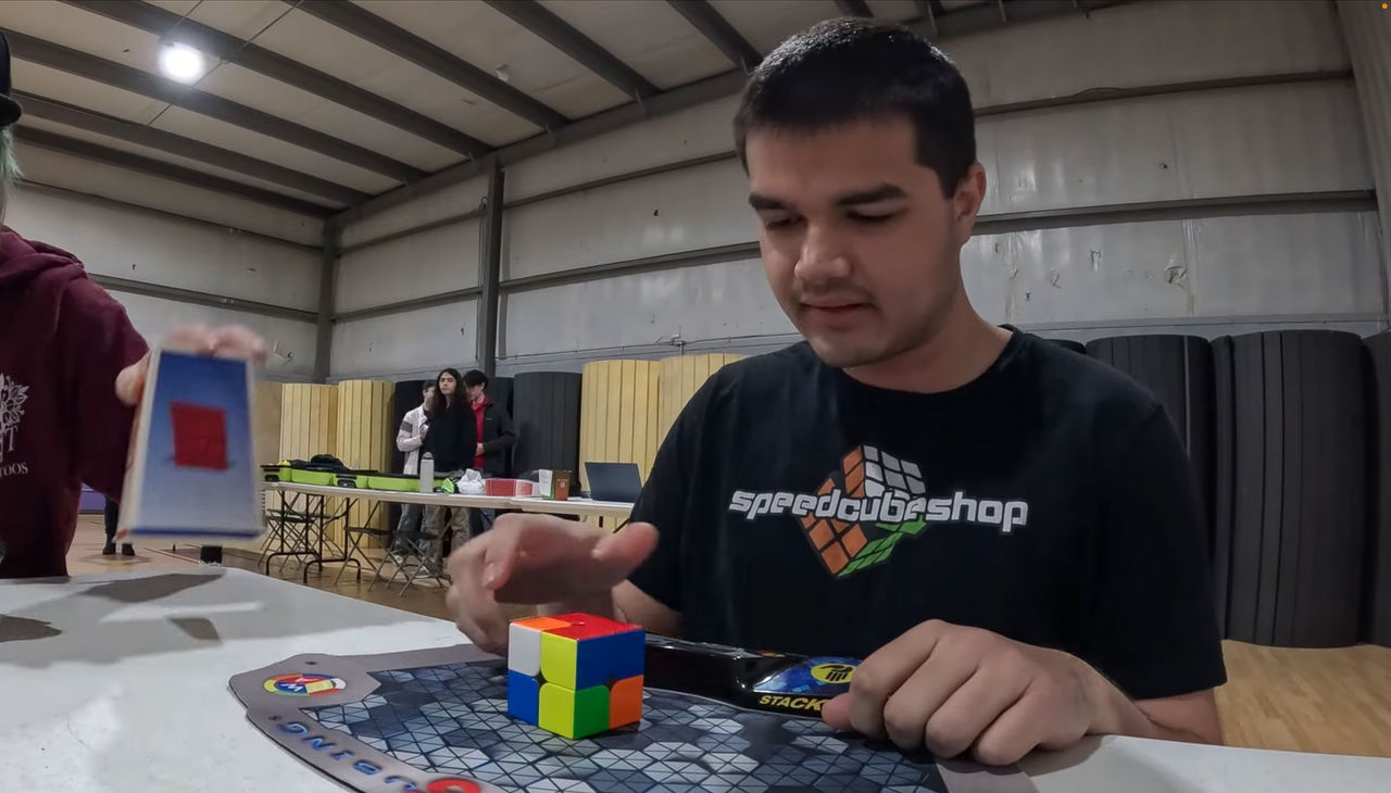 Sujan Feist sits in front of a 2x2 cube on a padded timer.