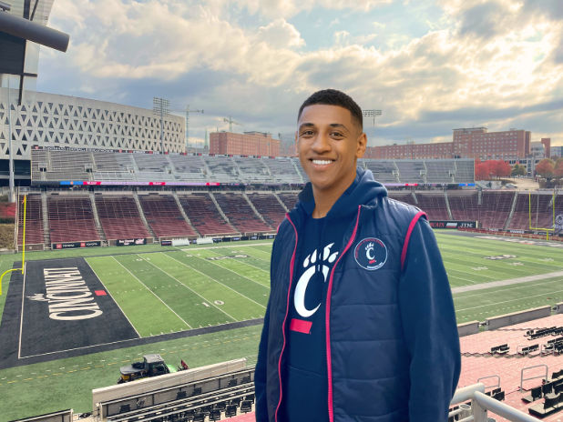 Person wearing UC puffy vest overlooking football field at Nippert Stadium