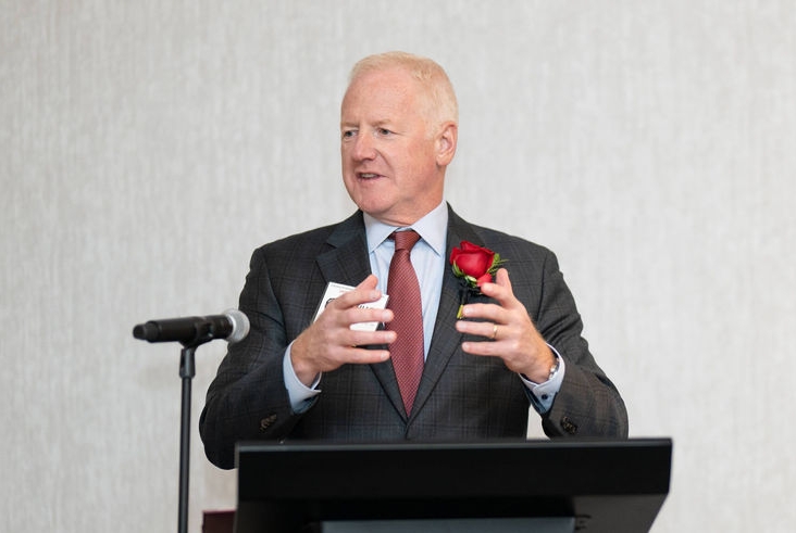 Chuch Hall stands at a podium talking.