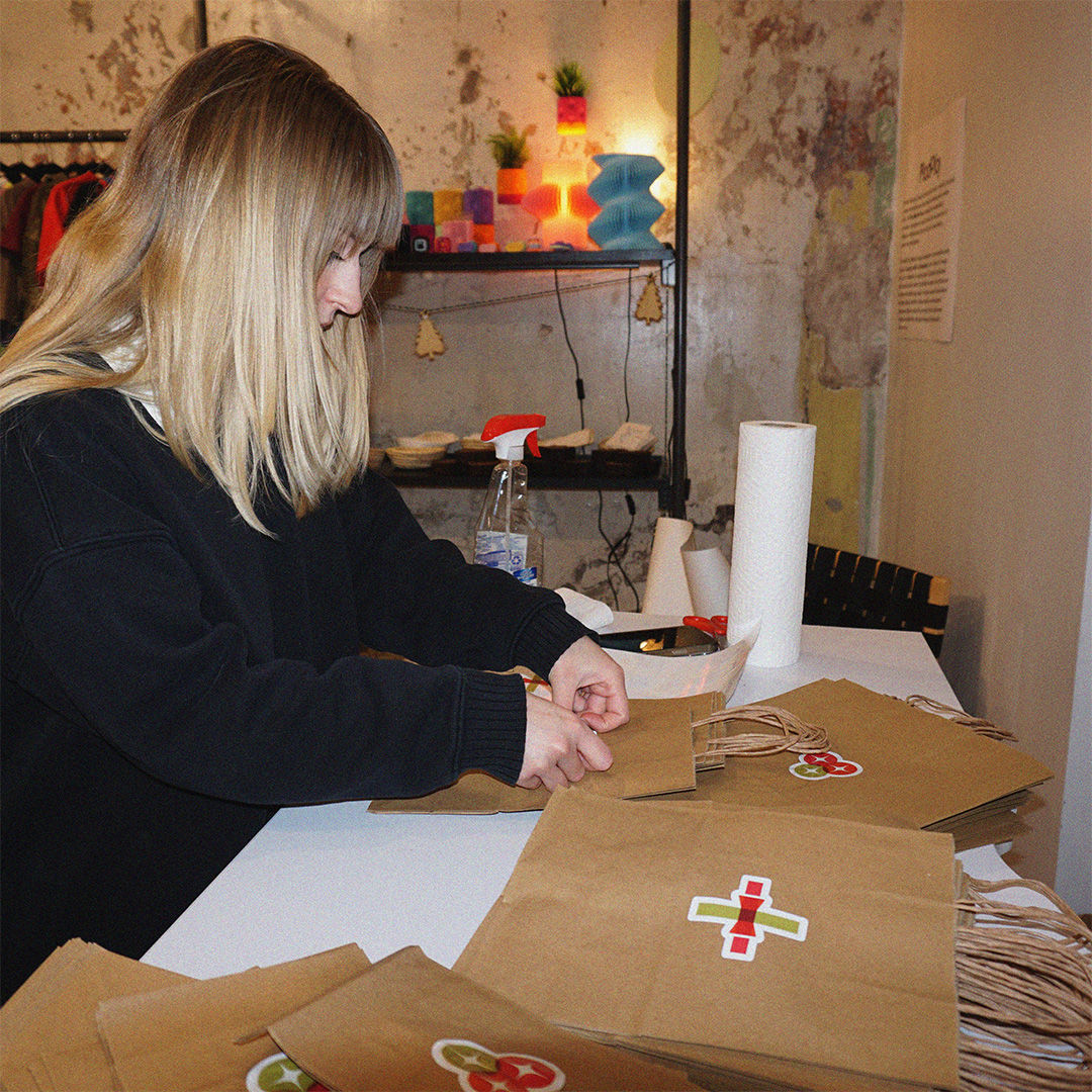 Ella Cronin working at a table and cutting paper to wrap products  