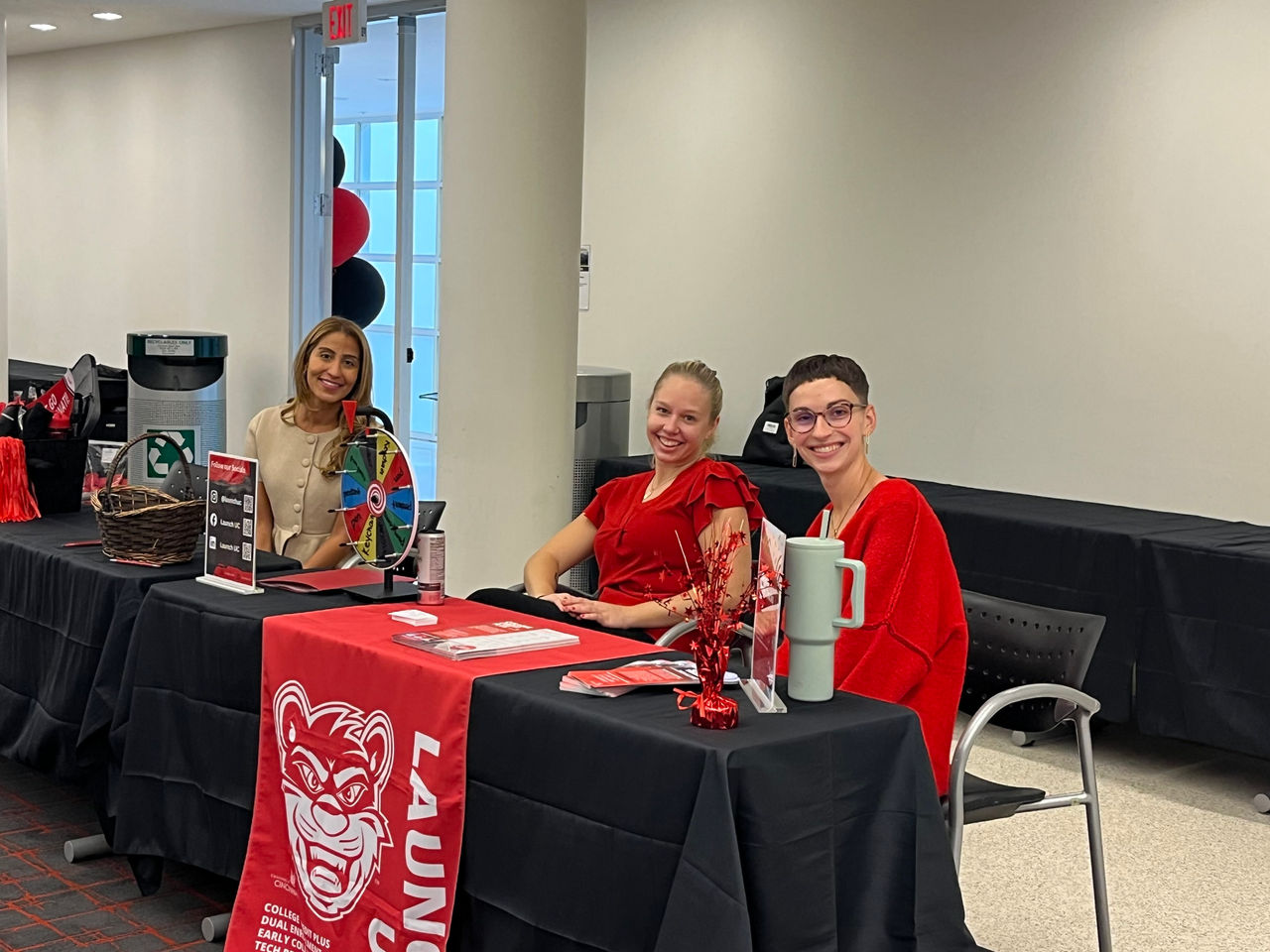 Students sit at a table in a high school and smile