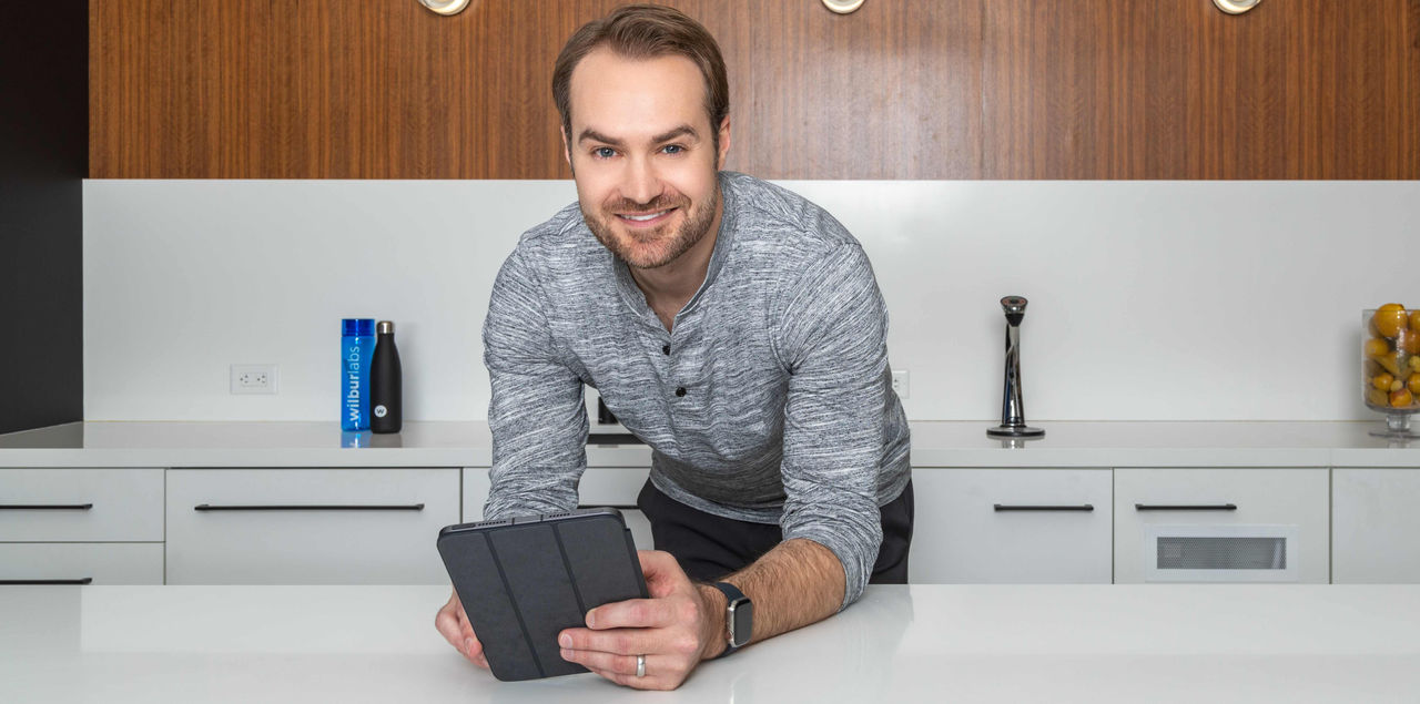 Phil Santoro in a gray long sleeve shirt holding a device.