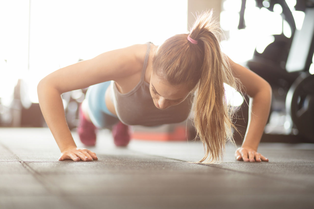 A woman exercises by doing a push-up on the floor
