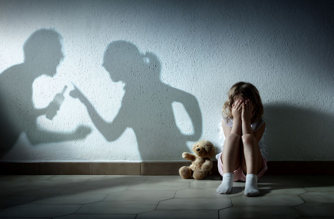 two people arguing with a sad child in the forefront 