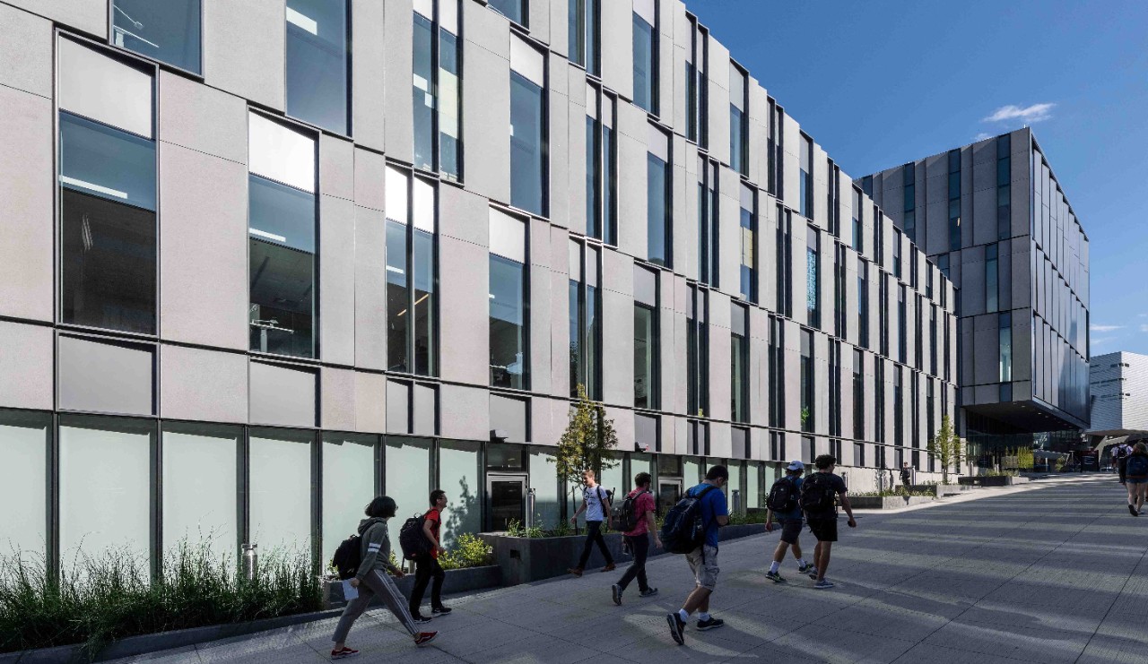 People walk on a path adjacent to the exterior of Lindner Hall.