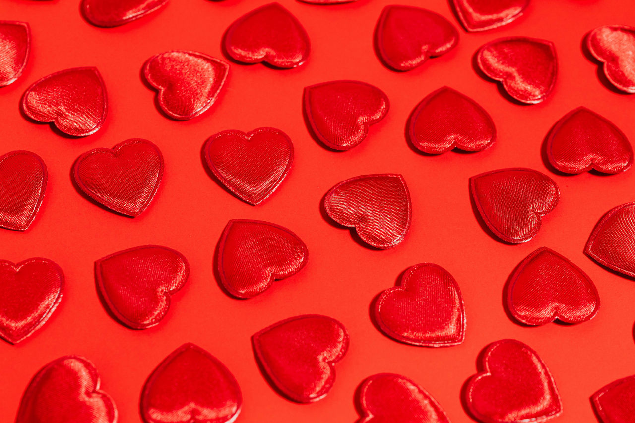 Red plush hearts laying on a red background