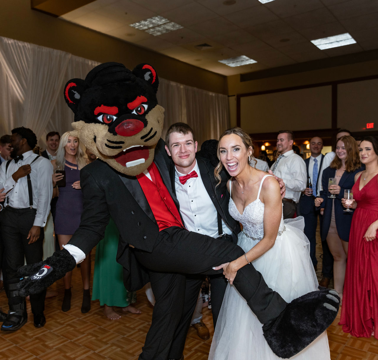 Taryn and Bryce Huskey posing with Bearcat at their wedding.