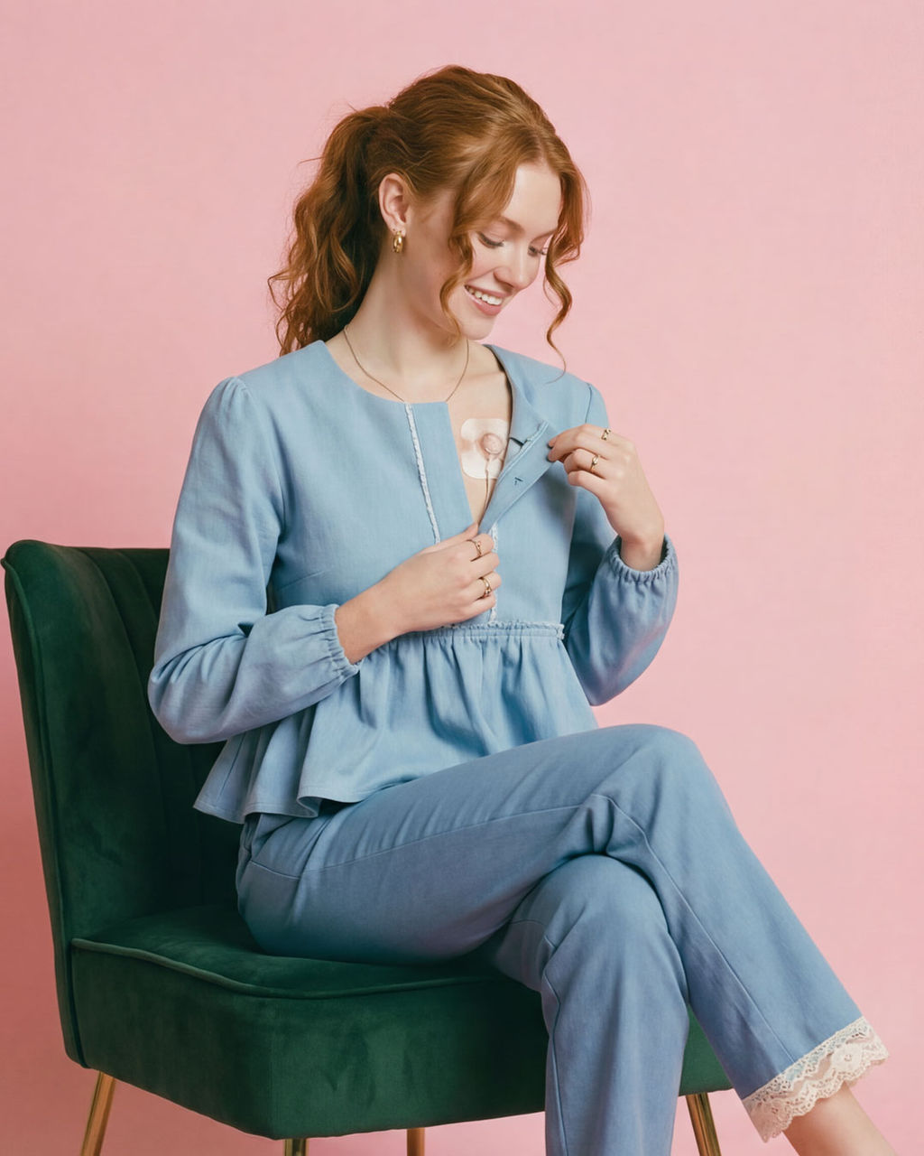 A young woman wearing a light blue blouse sits in a chair. She has a medical device of some kind on her chest.