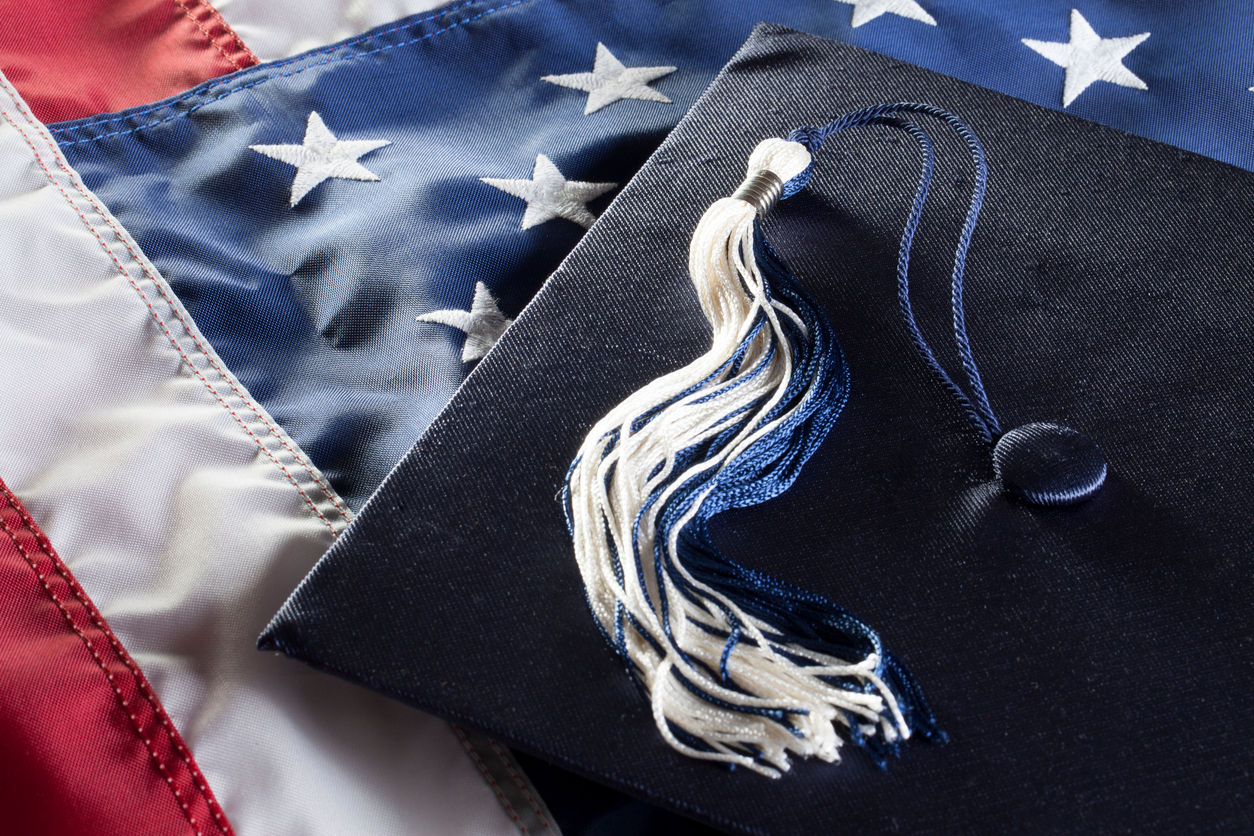 U.S. flag with graduation cap and tassle laid on top