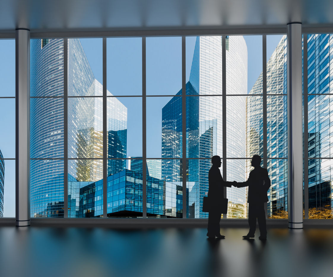 Business men shaking hands inside a business tower