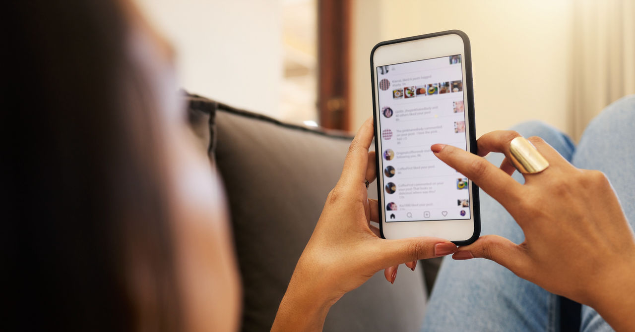 A person lying on a couch scrolls on her phone.