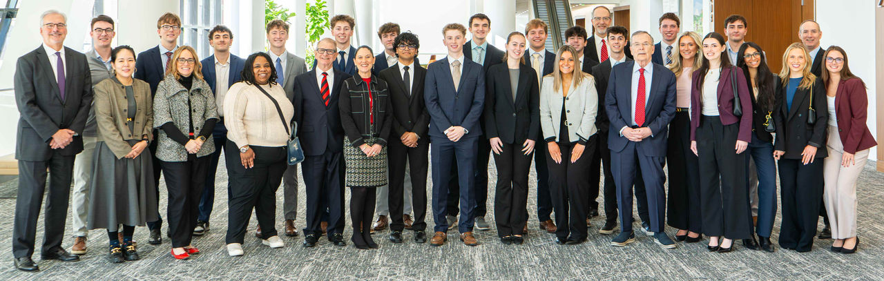 Student and real estate professionals pose for a group picture in a hallway.