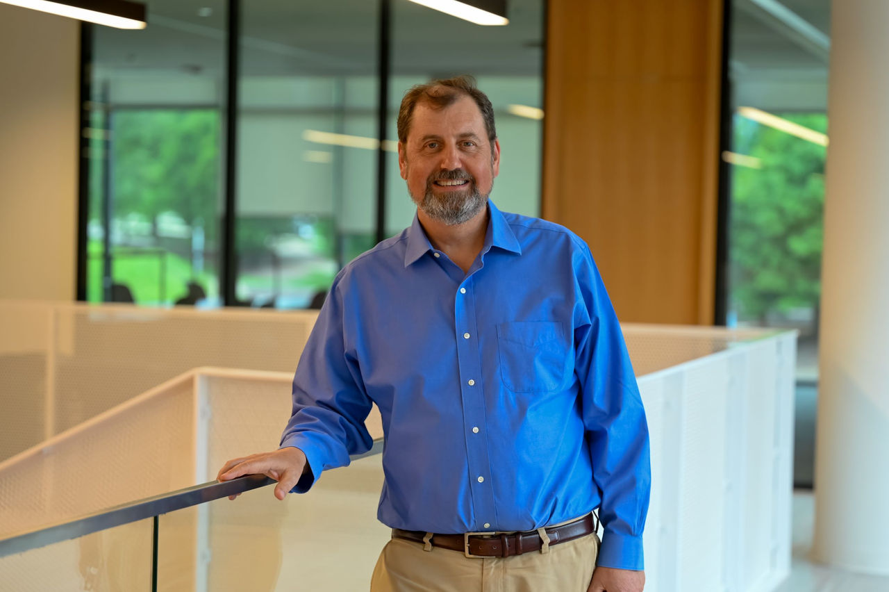 Neil Taylor is dressed in a coat and tie and shown standing in the UC College ofLaw.