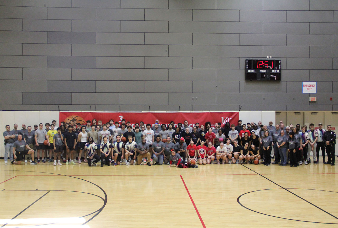 A large group of people pose on a basketball court.