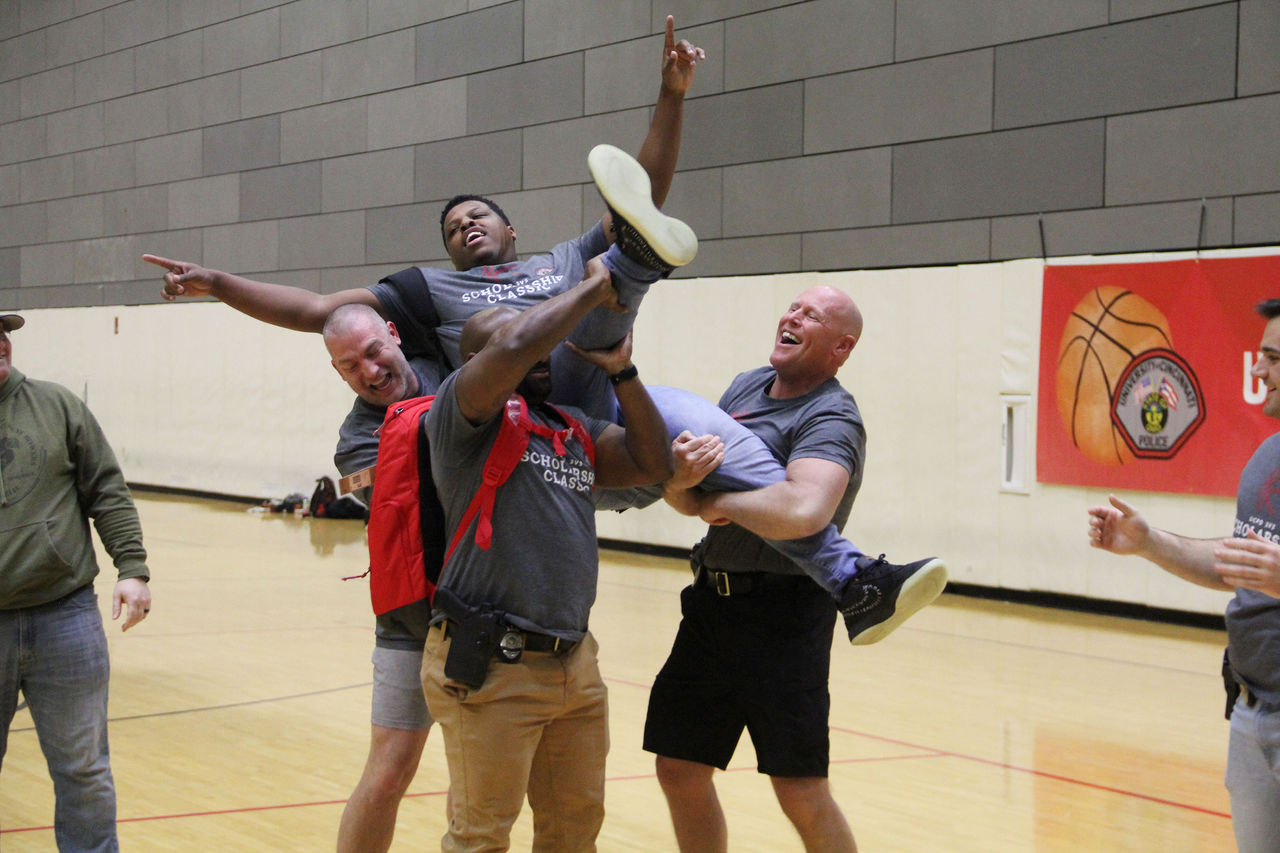 Three men, with excited expressions, lift an exuberant man into the air.
