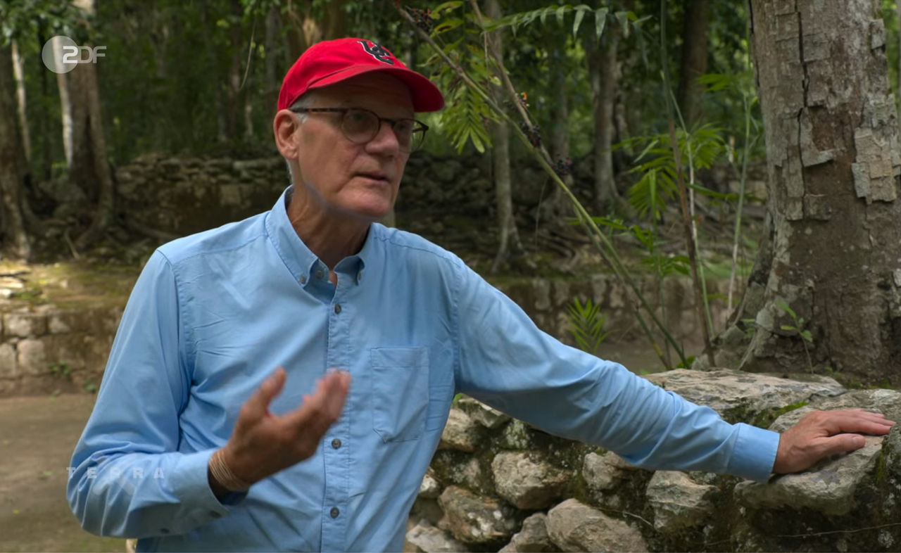 David Lentz wearing a UC ballcap talks to German TV at the ruins of an ancient Maya settlement.