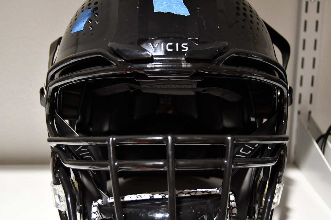 A closeup of the front of a football helmet marked with pieces of tape.