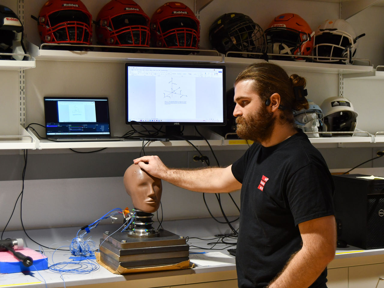 Sean Bucherl stands next to a test dummy on a lab bench.