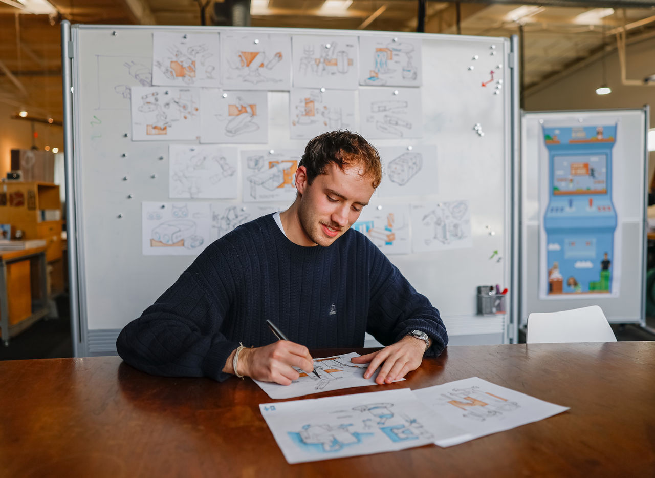 A co-op student works on a mock-up in front of a whiteboard in an office.