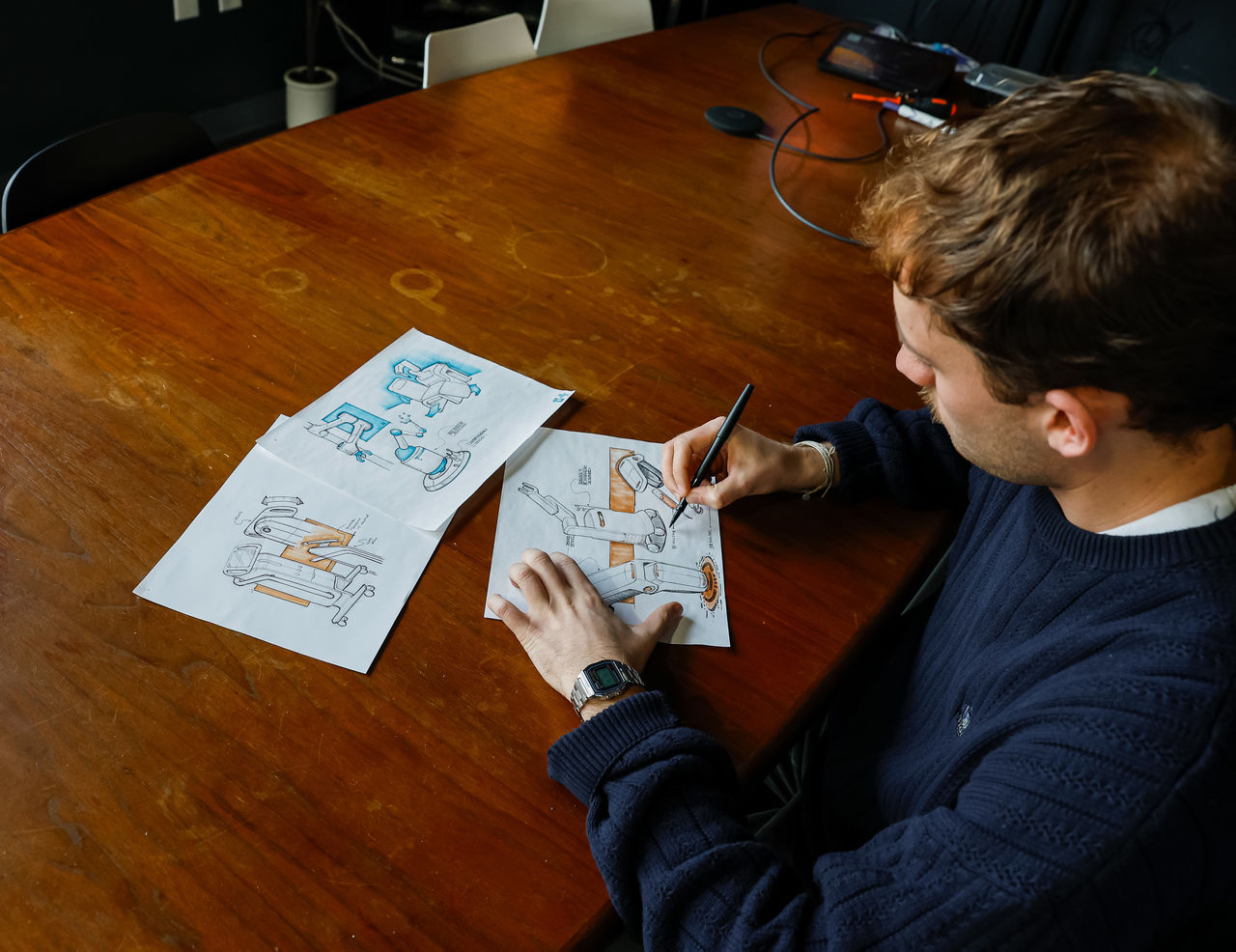 Titus Koesters sits at a table sketching.