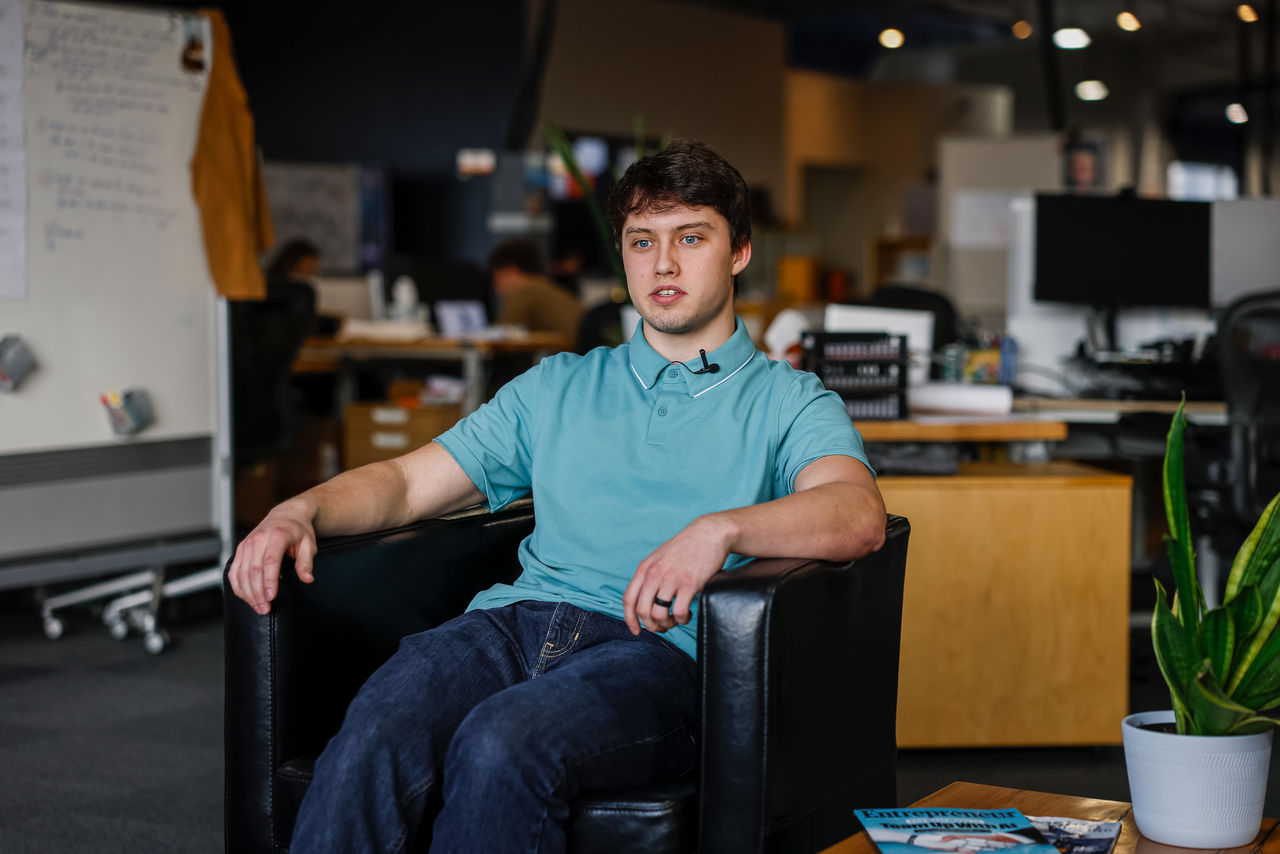 Connor Carlson sits talking in a large office space.