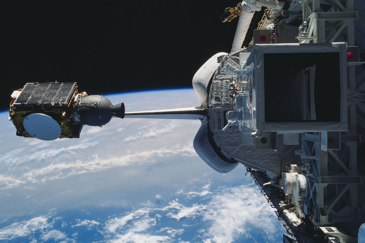 The space shuttle Discovery deploys Arabsat with the Earth and outer space in the background.