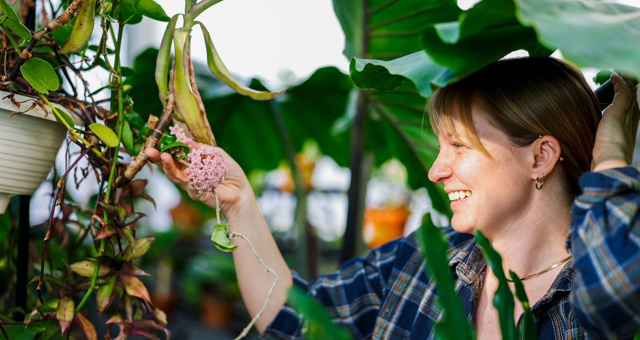 Audrey Trauth holds a flower in the greenhouse.