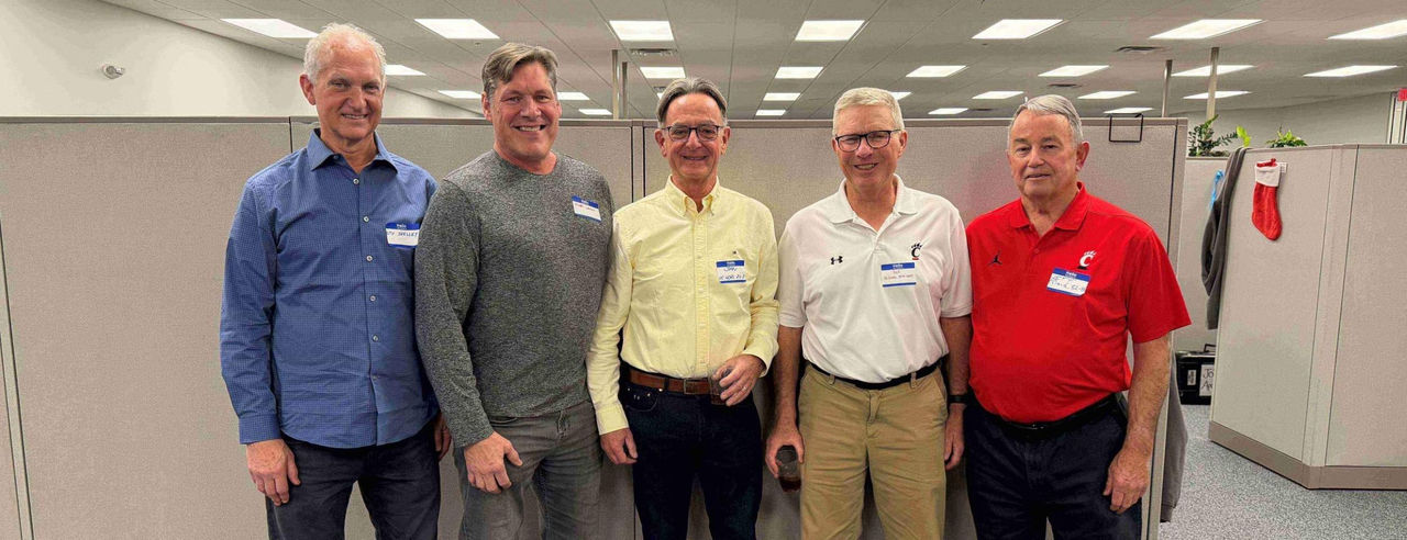 Five people standing and smiling.