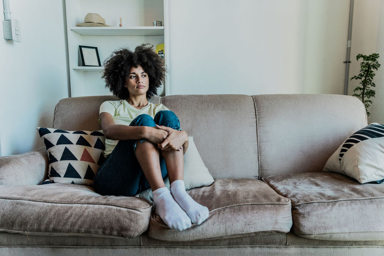 Young woman looking sad sitting on a couch